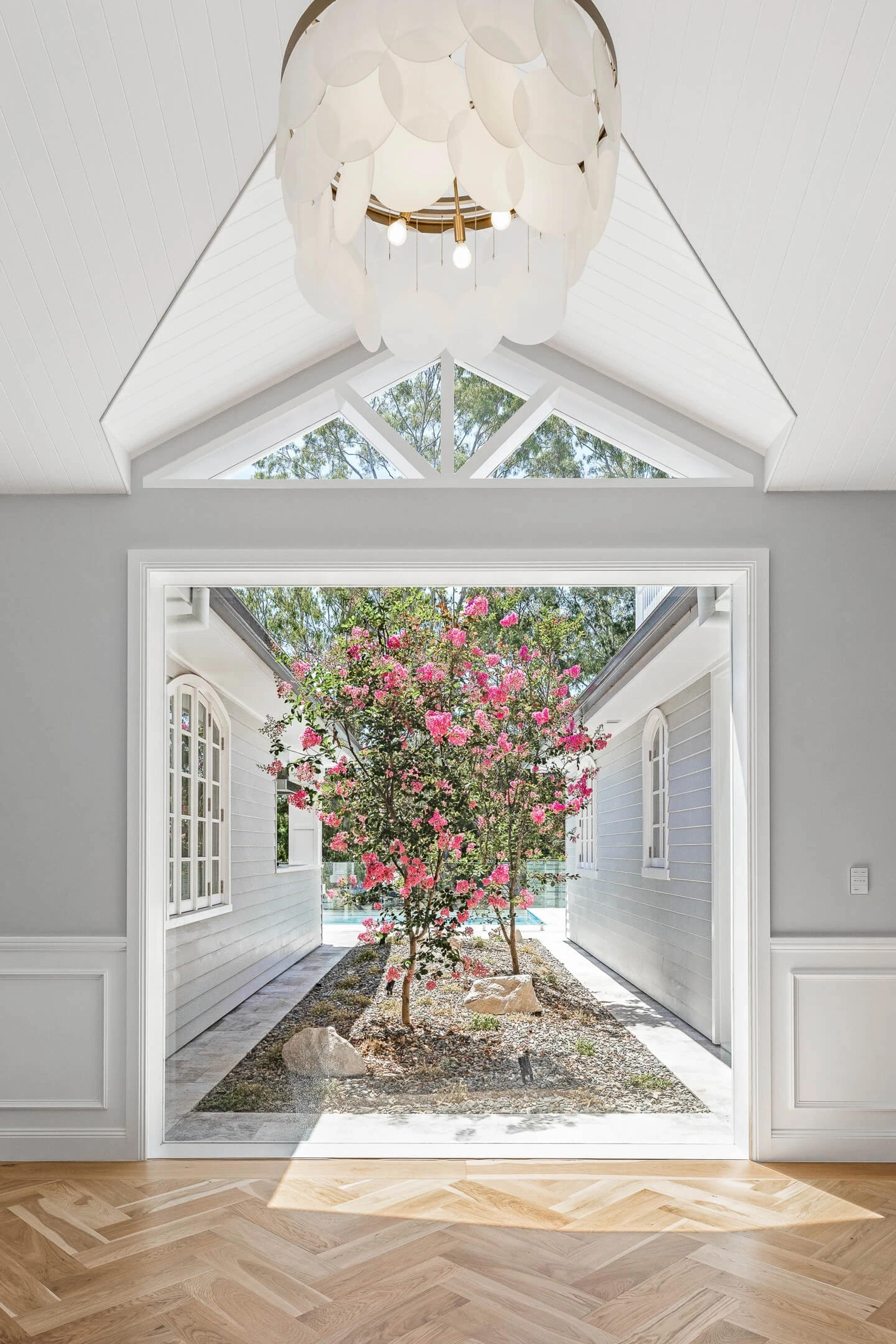 Interior window framing a courtyard with flowering pink tree