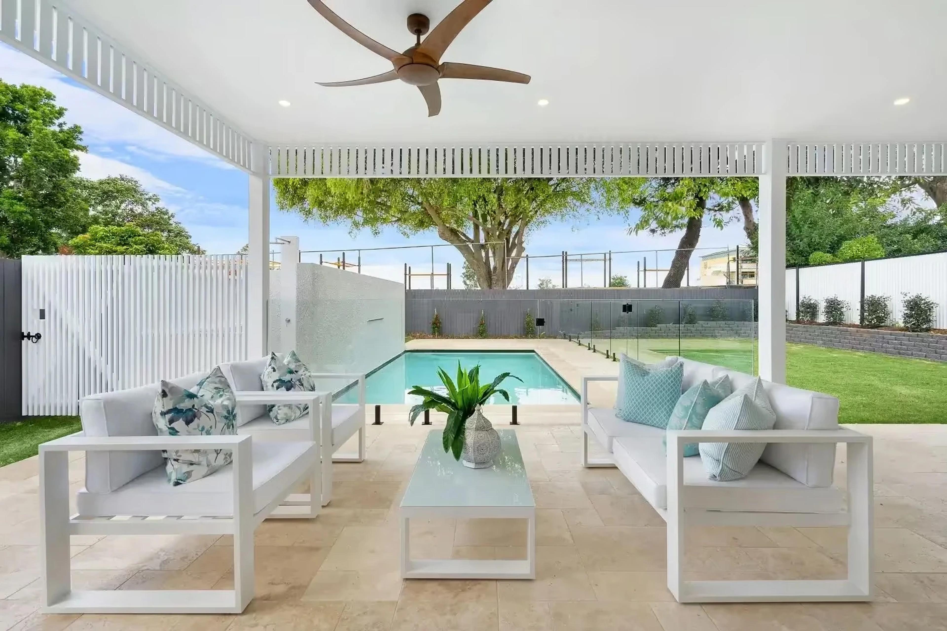 Covered outdoor lounge overlooking pool and garden