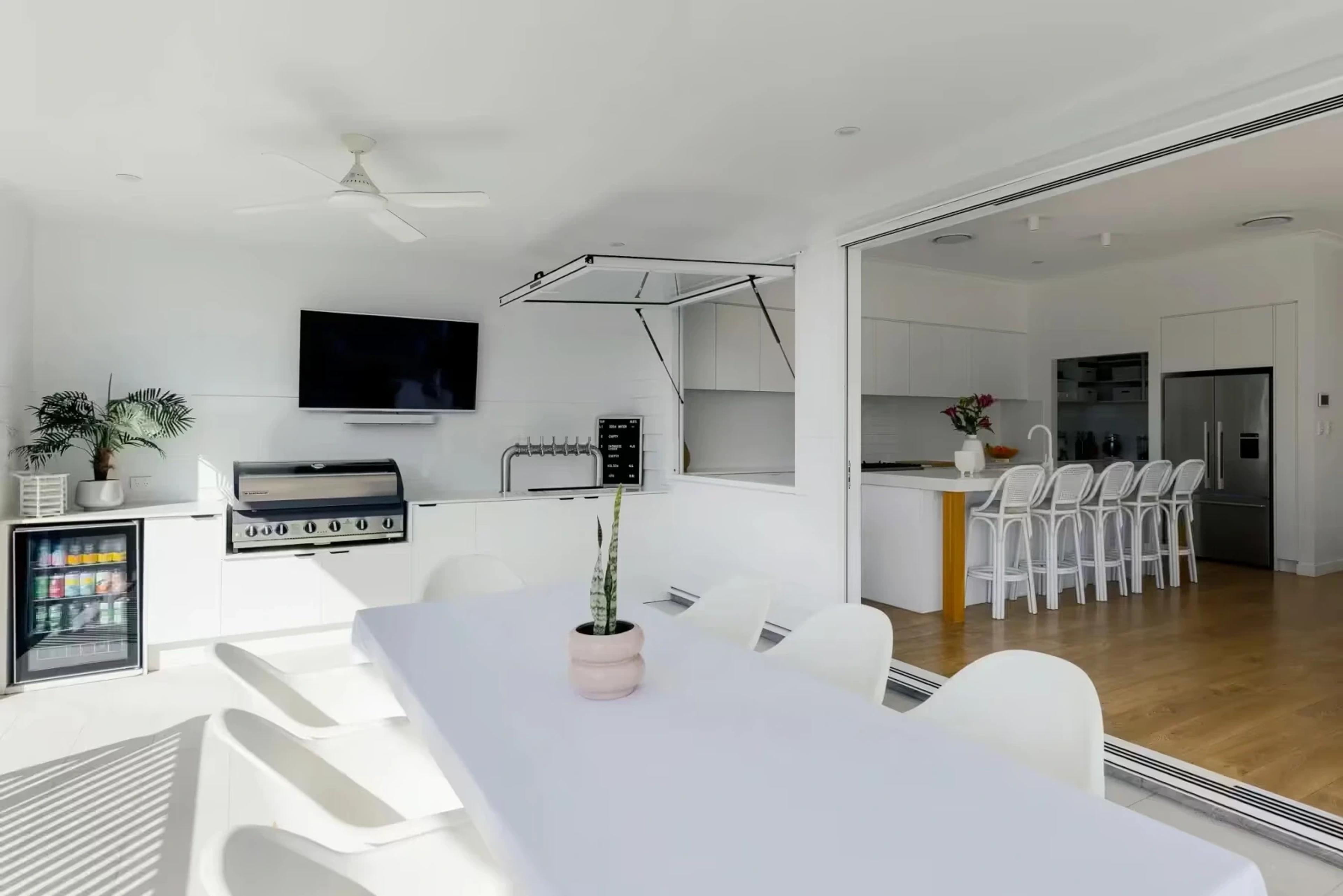 White outdoor kitchen with barbecue opening to indoor kitchen