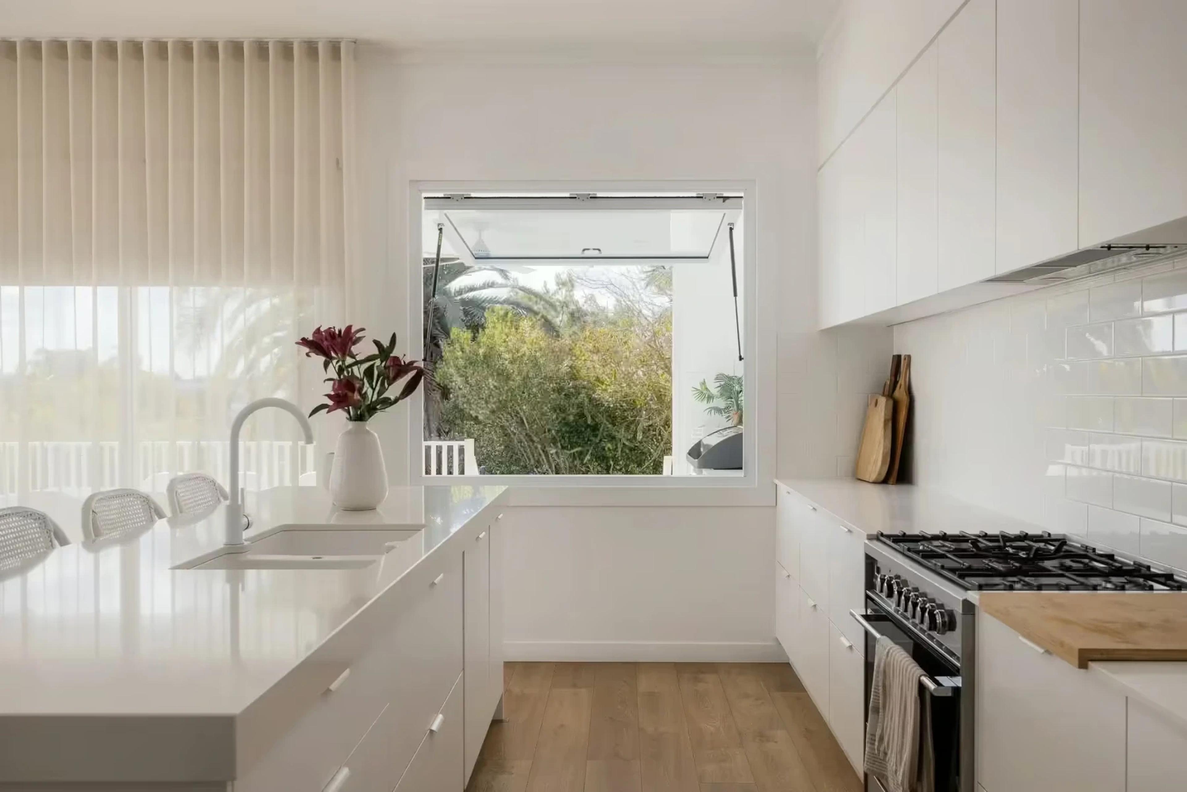 White kitchen with gas cooktop and awning window to garden