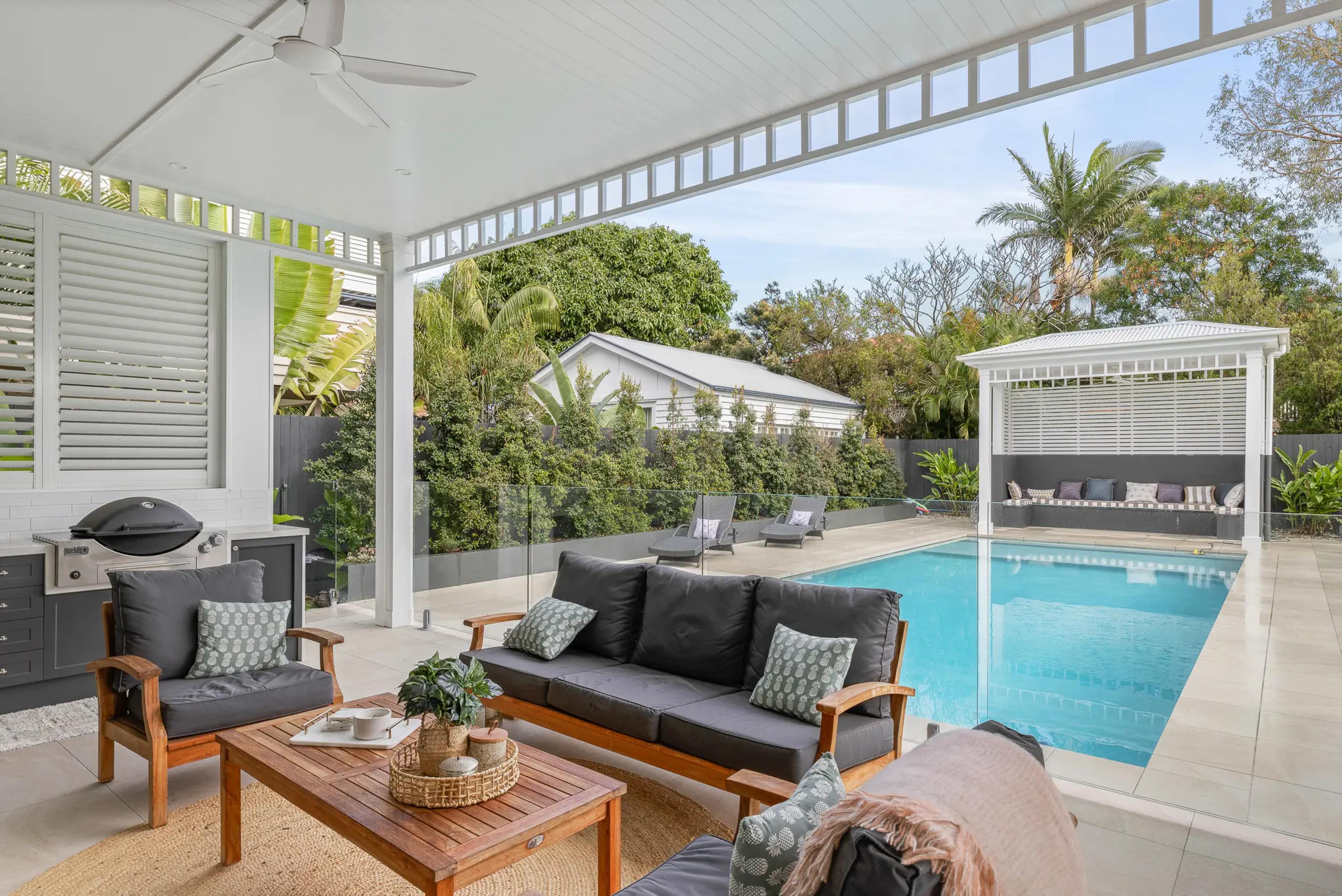 Covered outdoor lounge and barbecue overlooking swimming pool and cabana