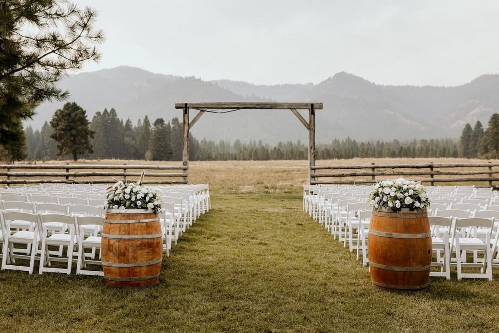 Ceremony set with white chairs, wine barrels, and the mountains behind
