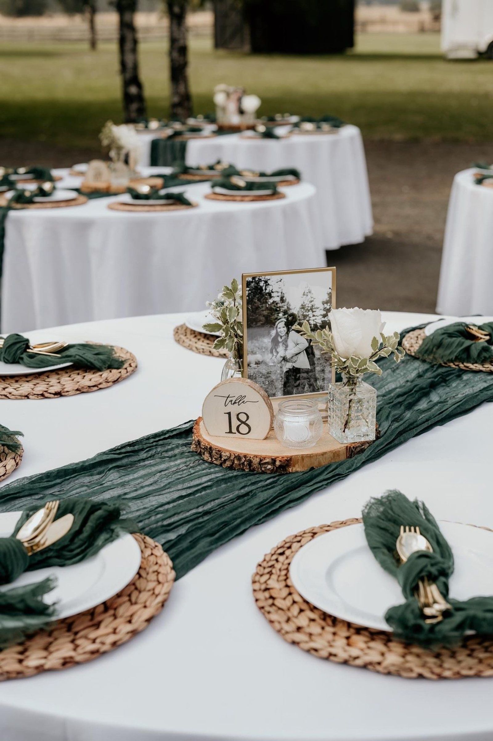 Reception table with a green runner, wood rounds, and gold flatware