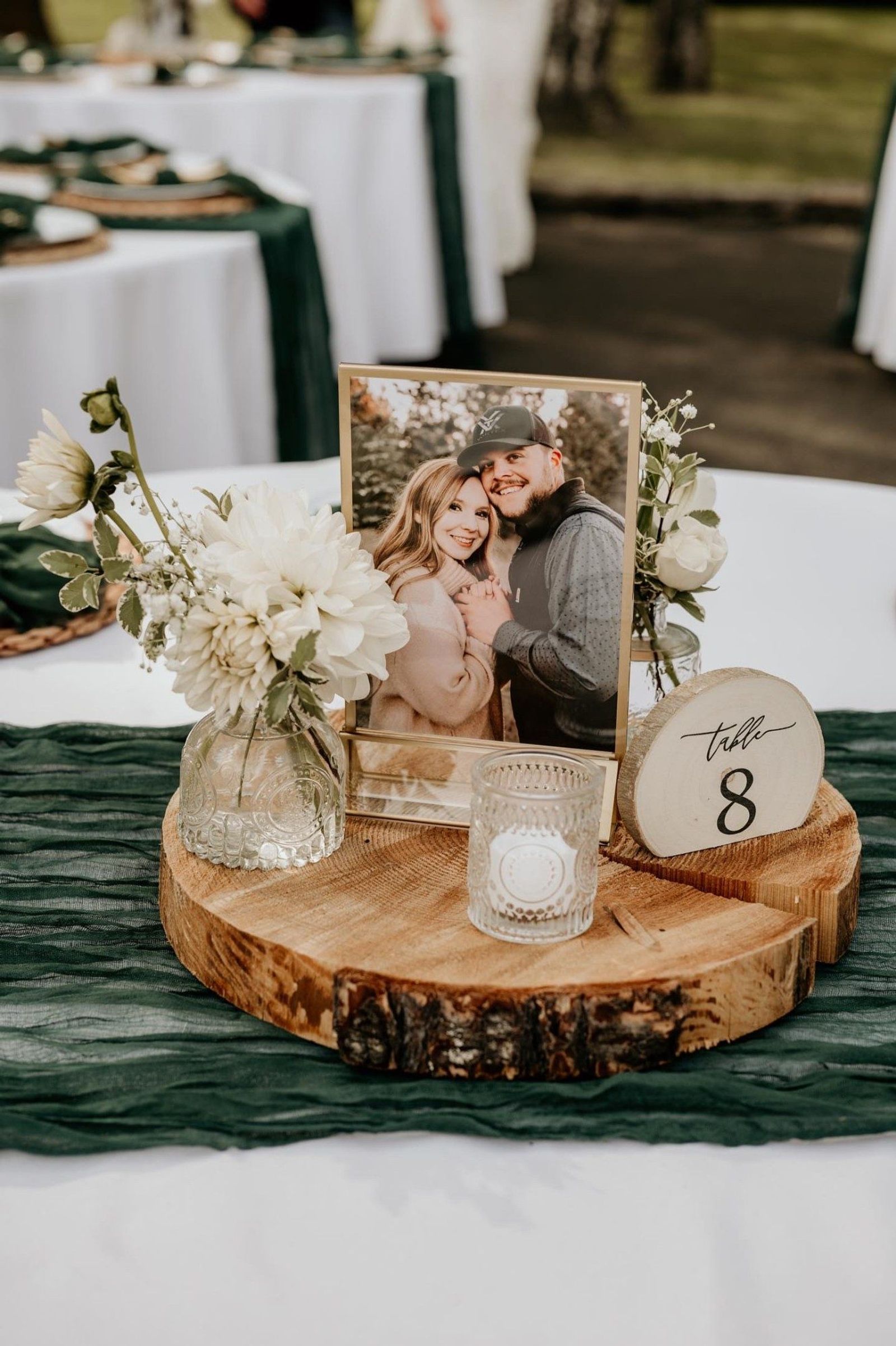 Table centerpiece with a framed photo, dahlias, and a wood round