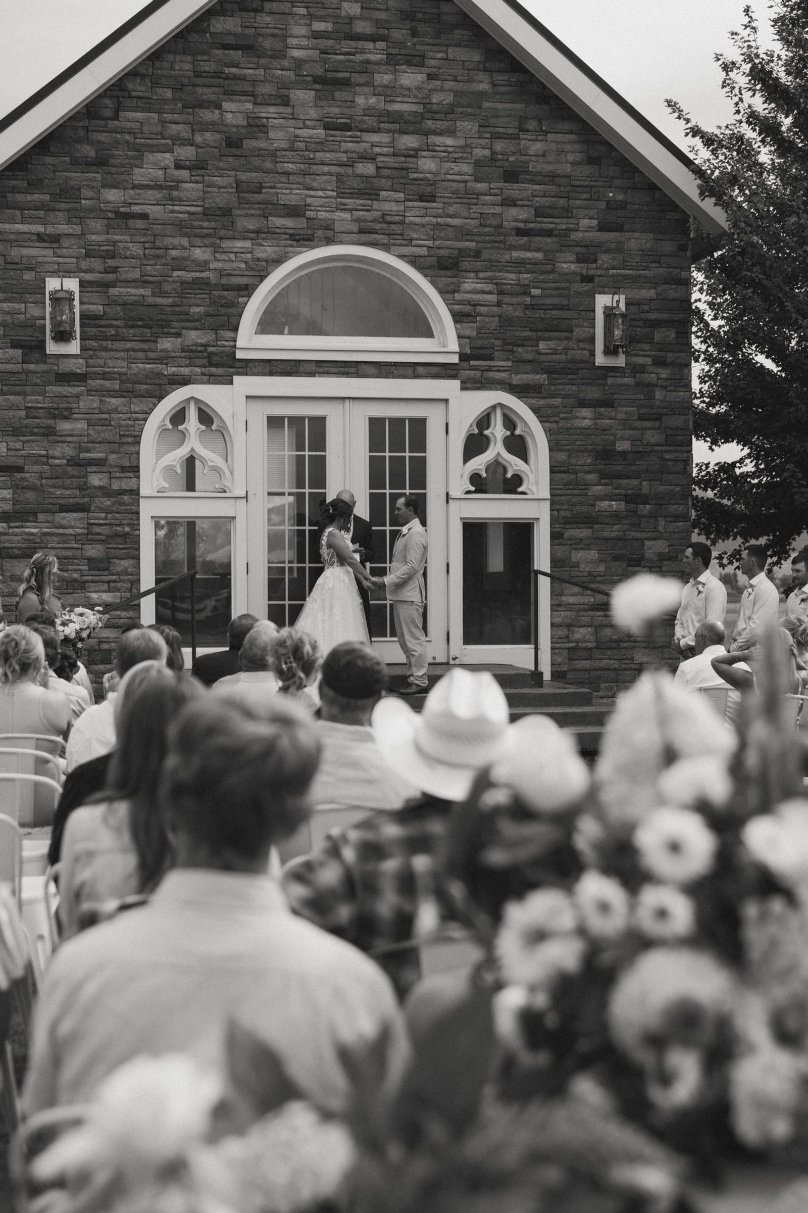 Black and white ceremony outside the stone chapel