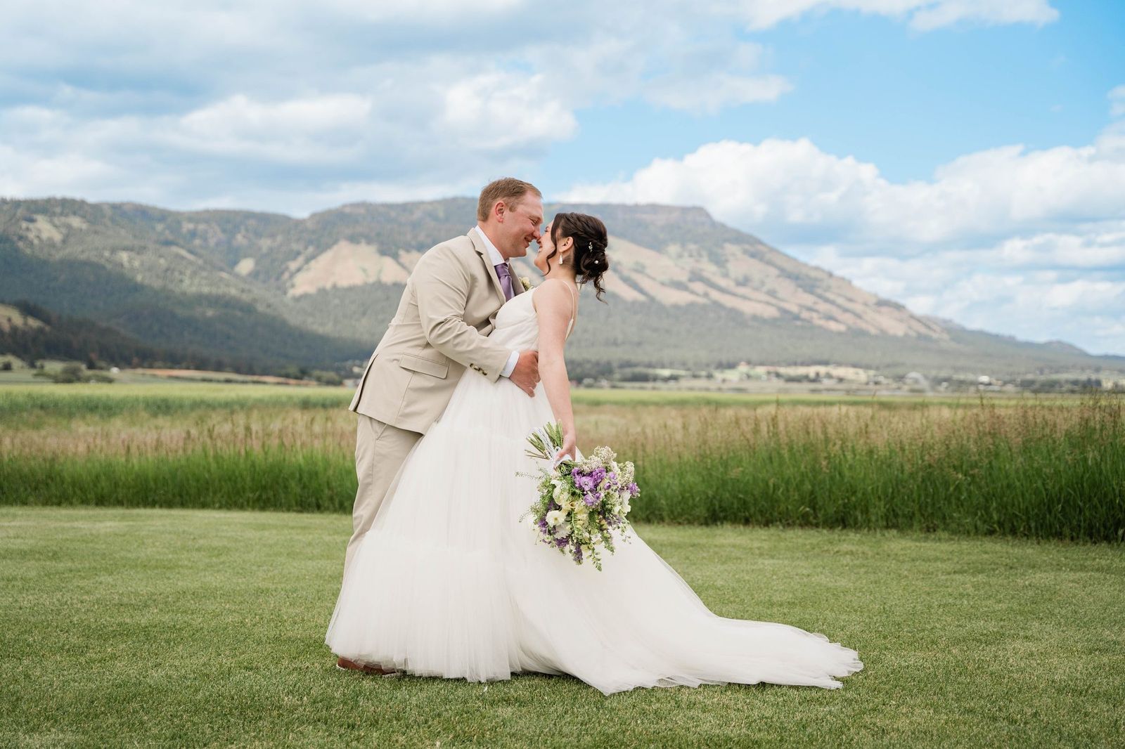 Couple dipping for a kiss with the mountains behind them