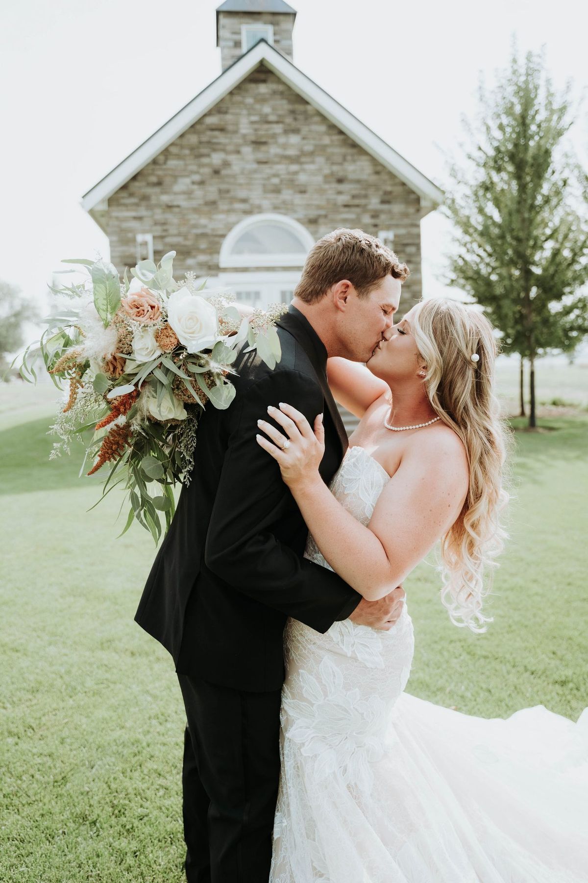 Bride and groom sharing a kiss with her bouquet