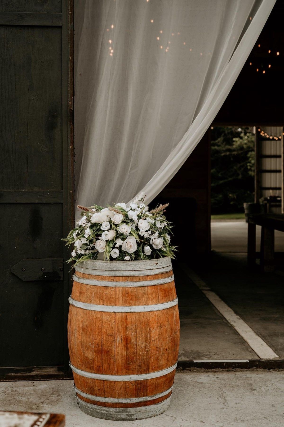 Wine barrel with white florals at the barn door