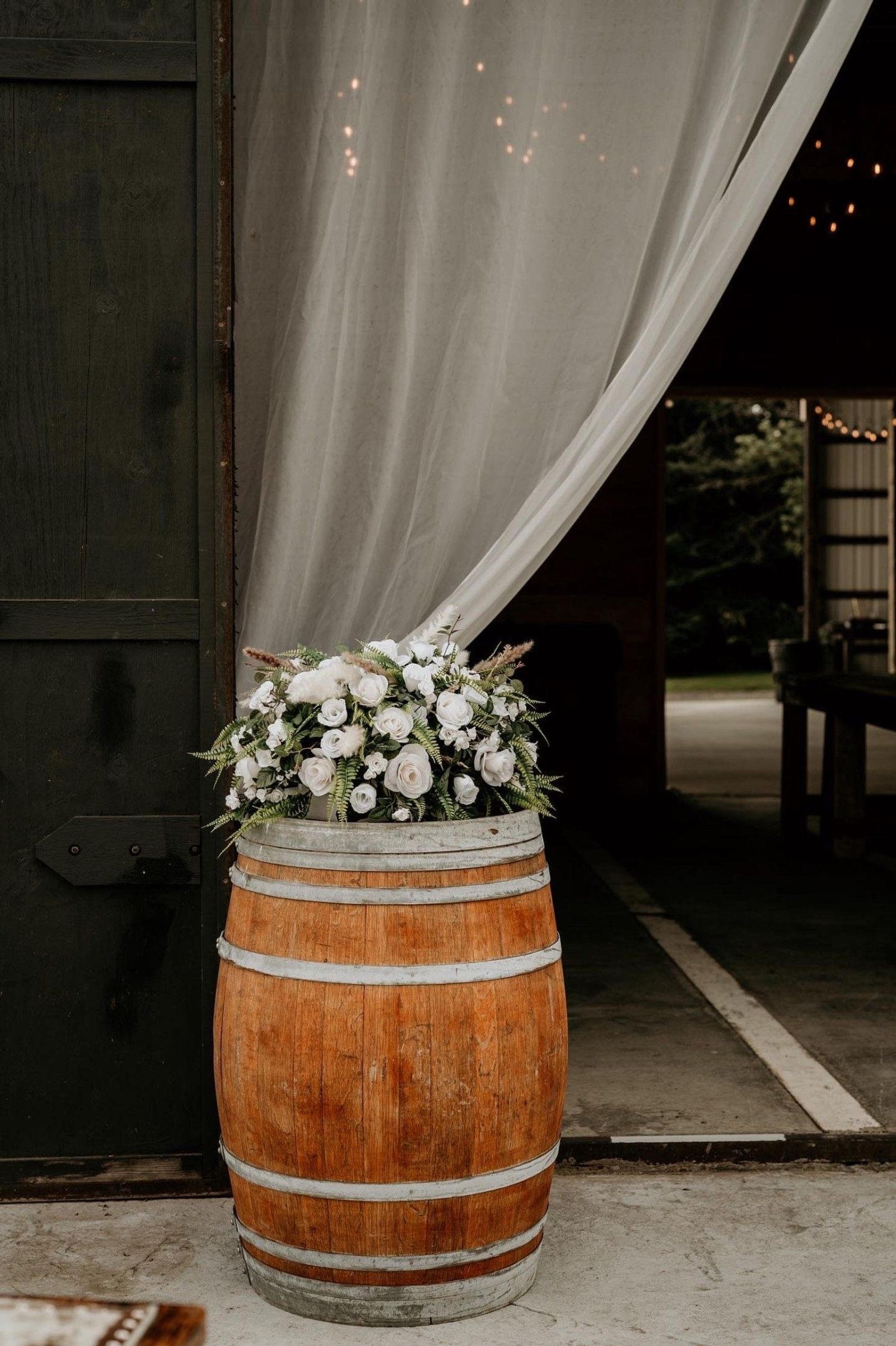 Wine barrel with white florals at the barn door