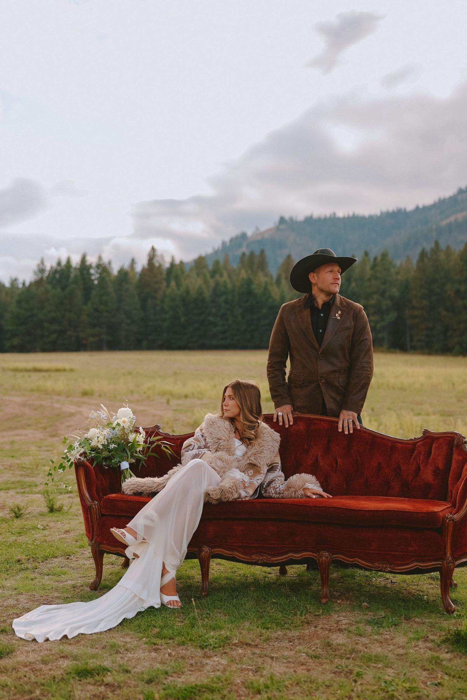 Couple on a red velvet couch in an open field