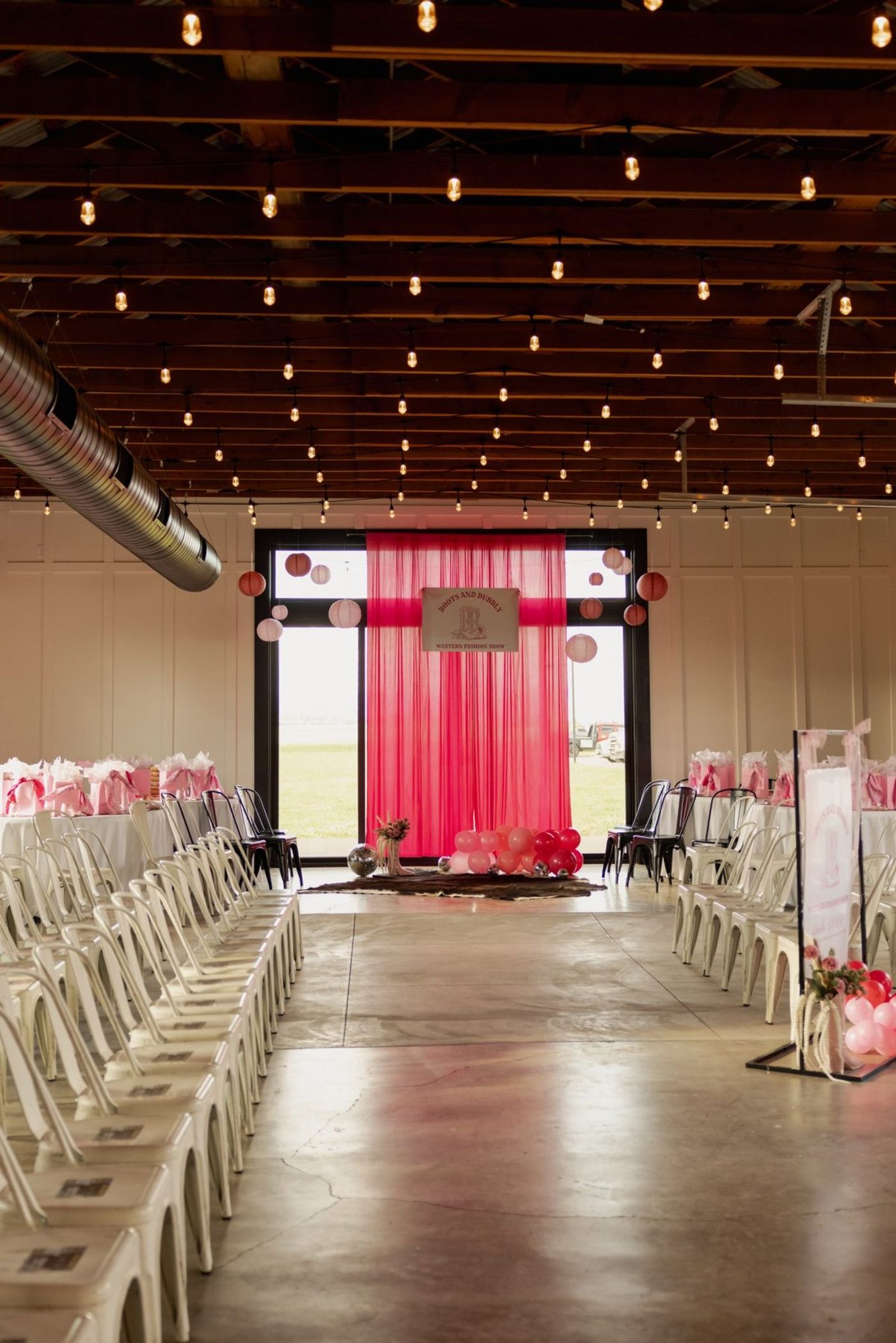 The room set for the show with the pink backdrop and rows of chairs
