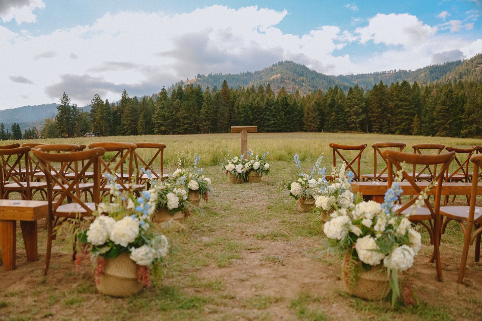 Ceremony set with wooden chairs and florals below the mountains