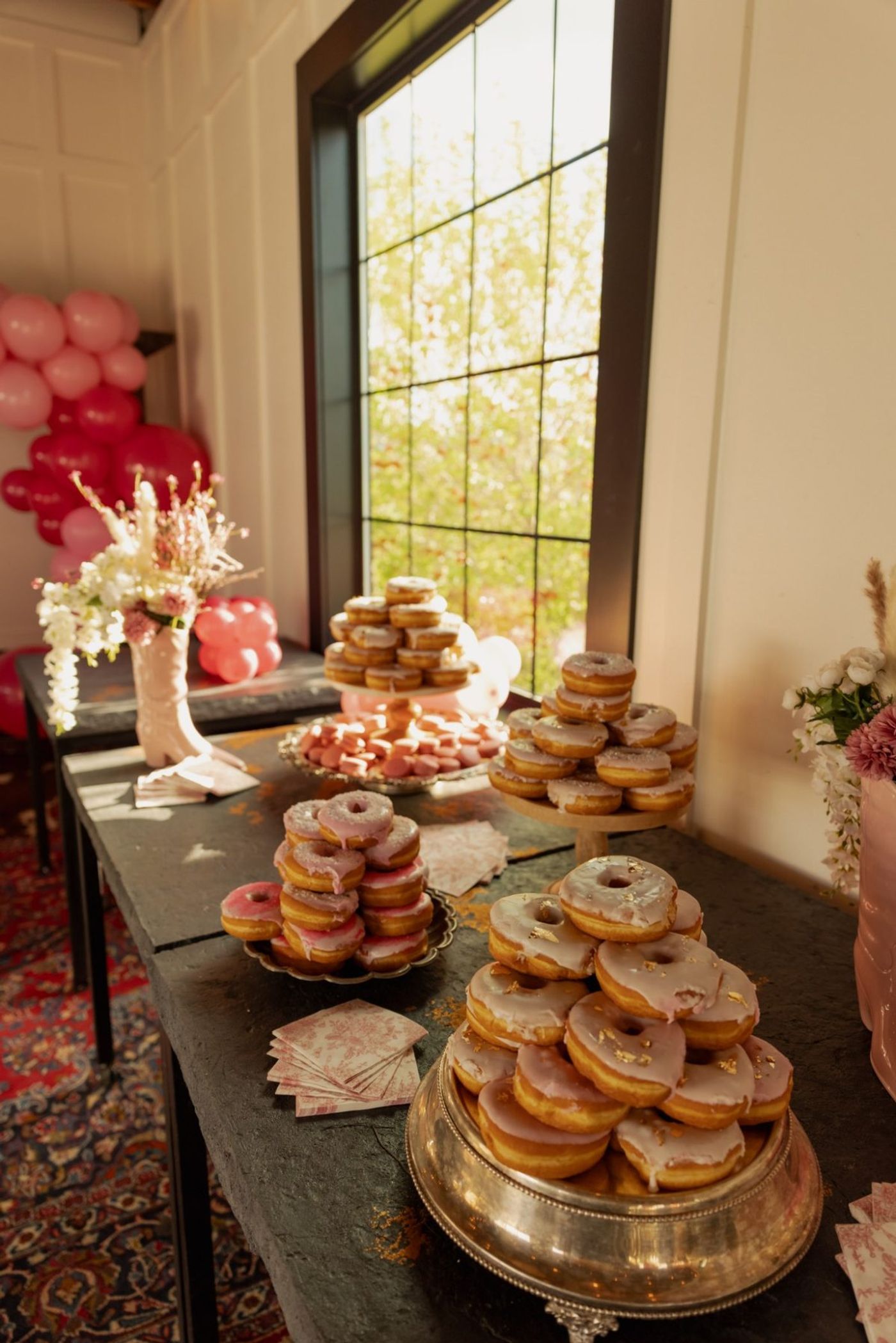 The dessert table with donut towers, macarons, and balloons