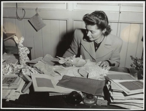 A teacher checks needlework at an overcrowded desk