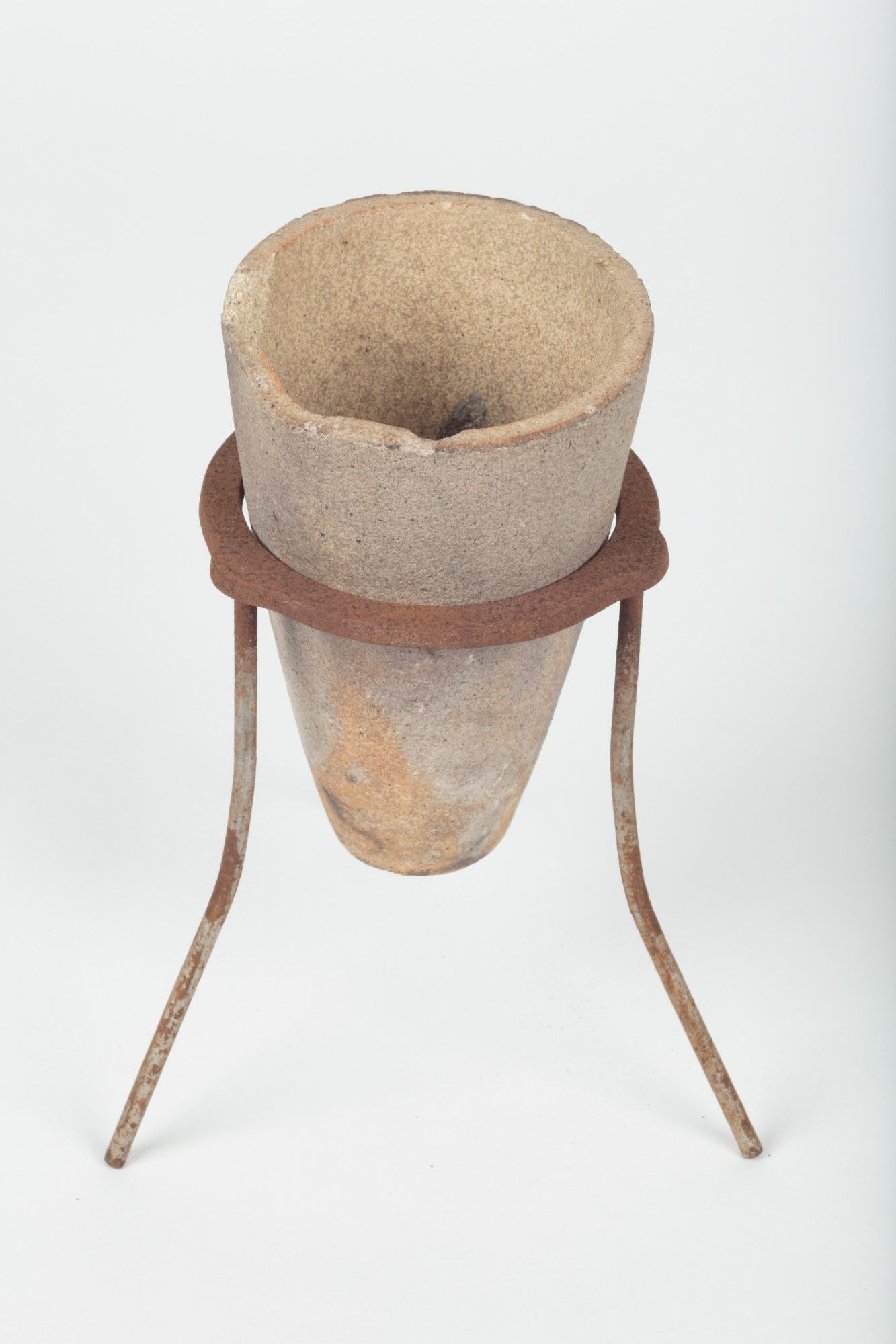 A small deep terracotta pot sits on a tripod