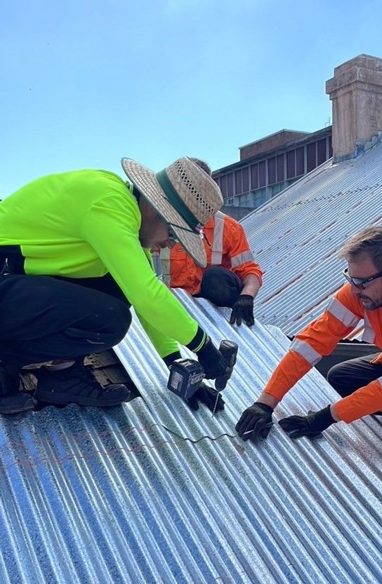 Workers carrying out repairs on a tin roof