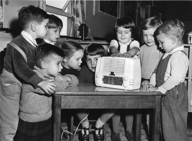 Group of children huddled around a radio
