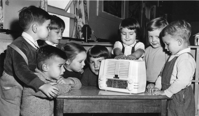 Group of children huddled around a radio