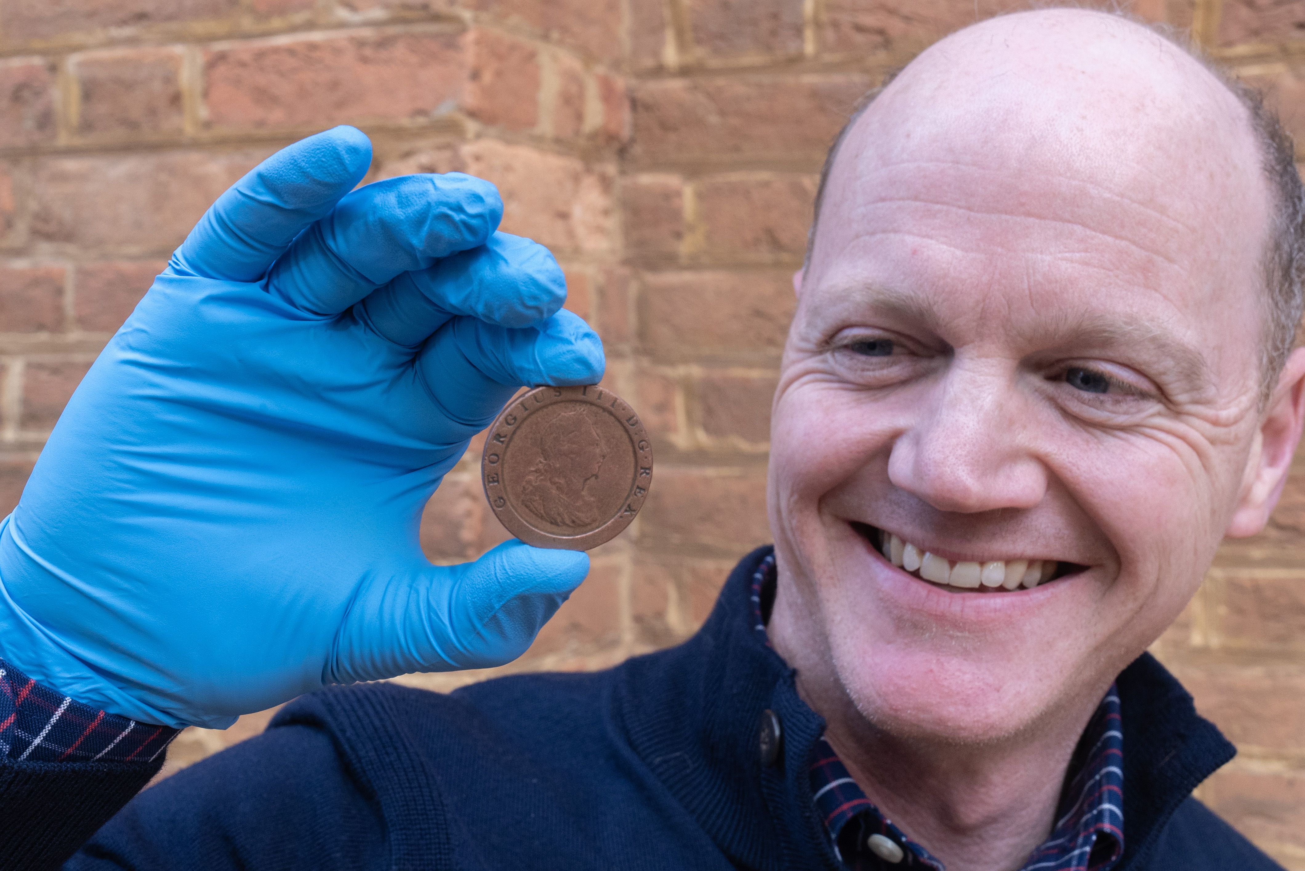 Photo of a man holding an engraved coin