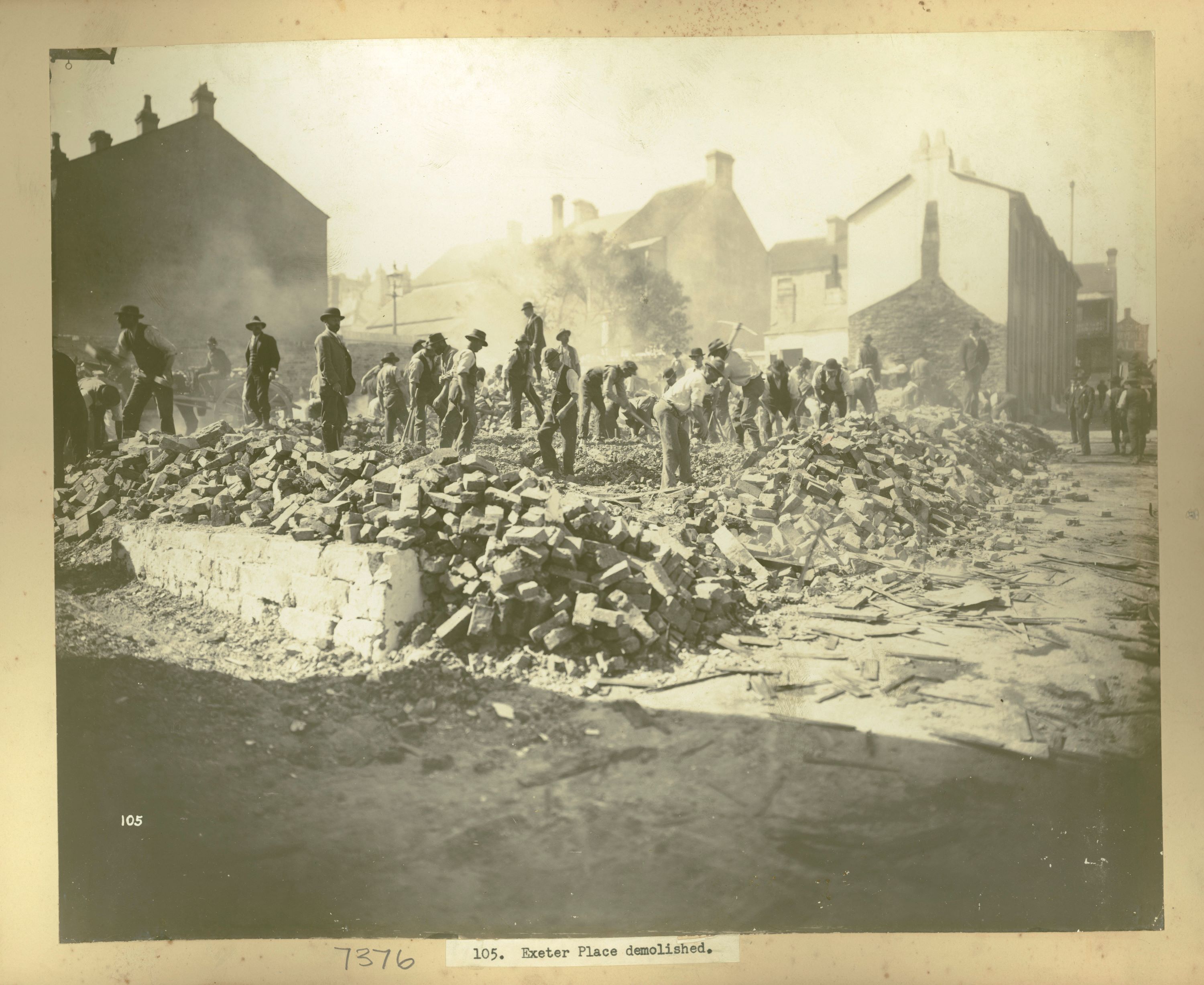 Workers stand in the rubble of a demolished building 
