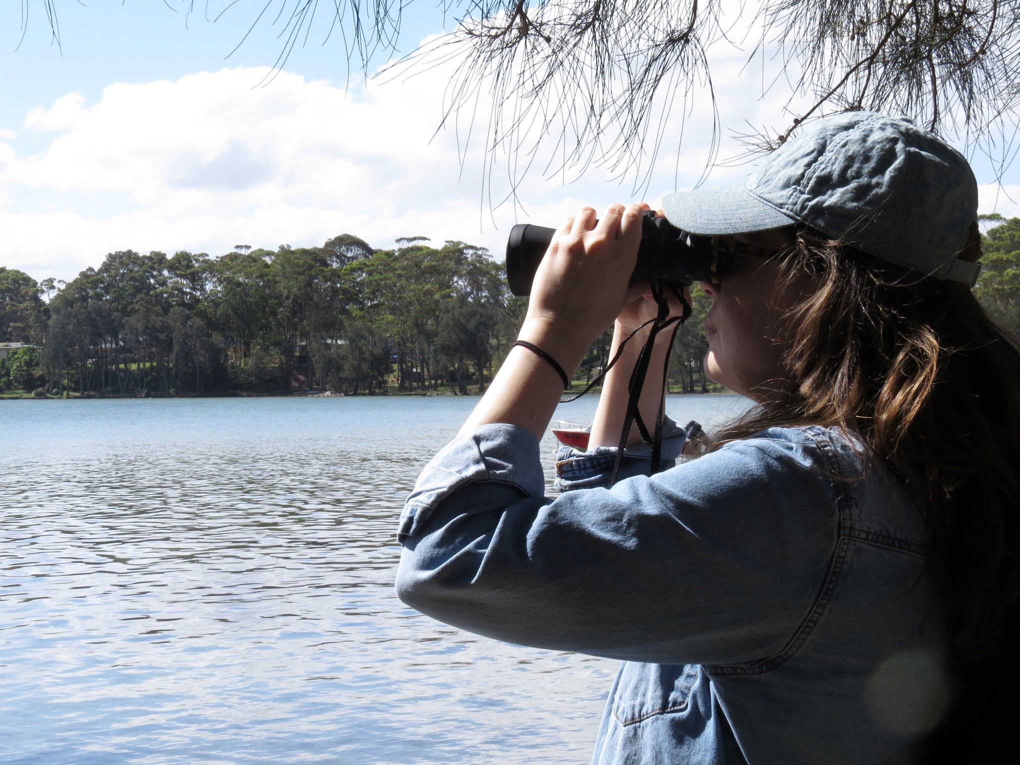 A woman looks through binoculars over a waterway