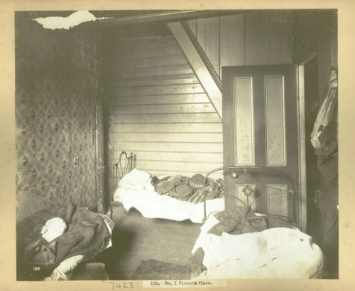 A small bedroom with three single, metal-framed beds