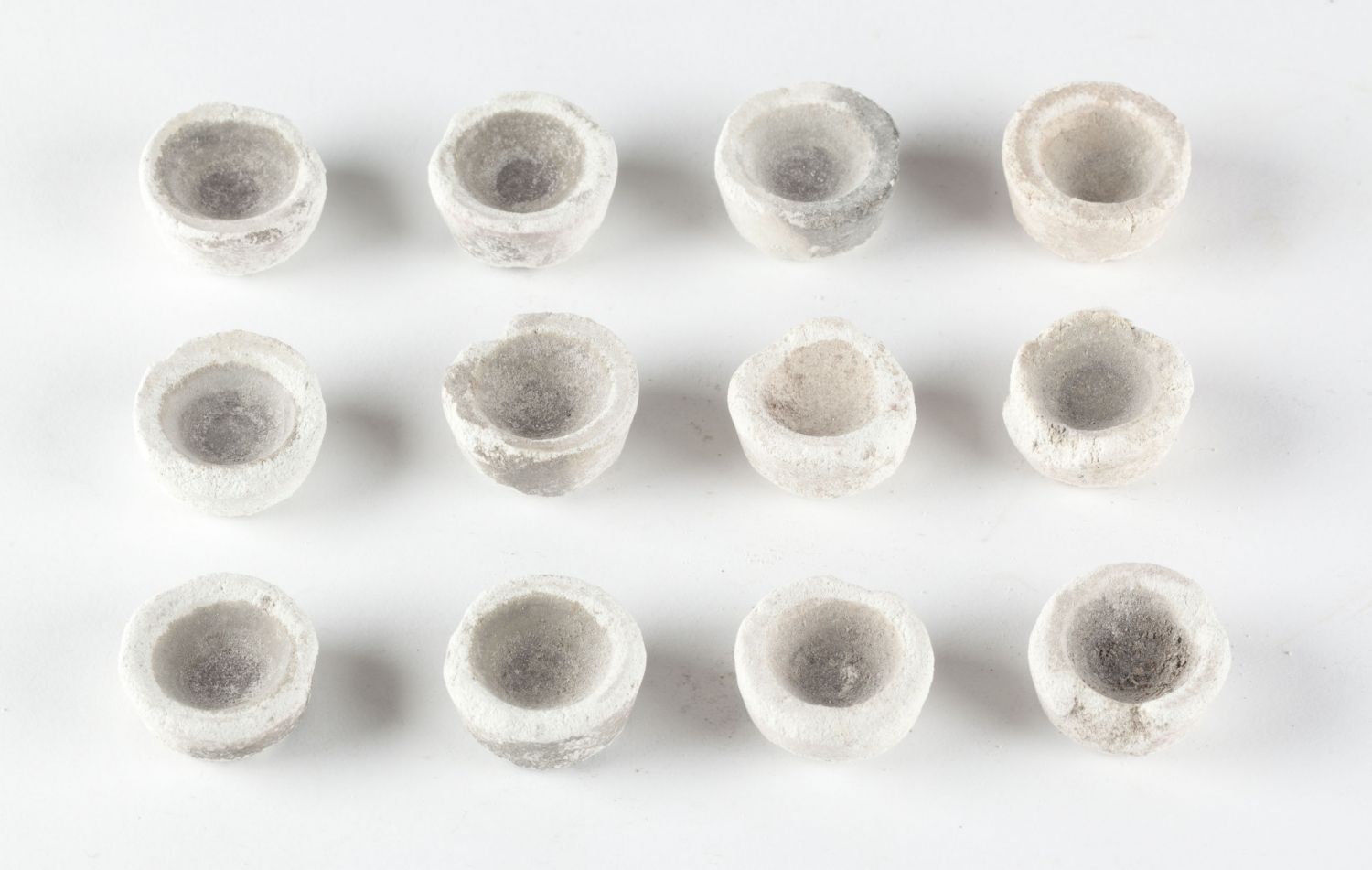 A group of 12 think rimmed cups on a white background