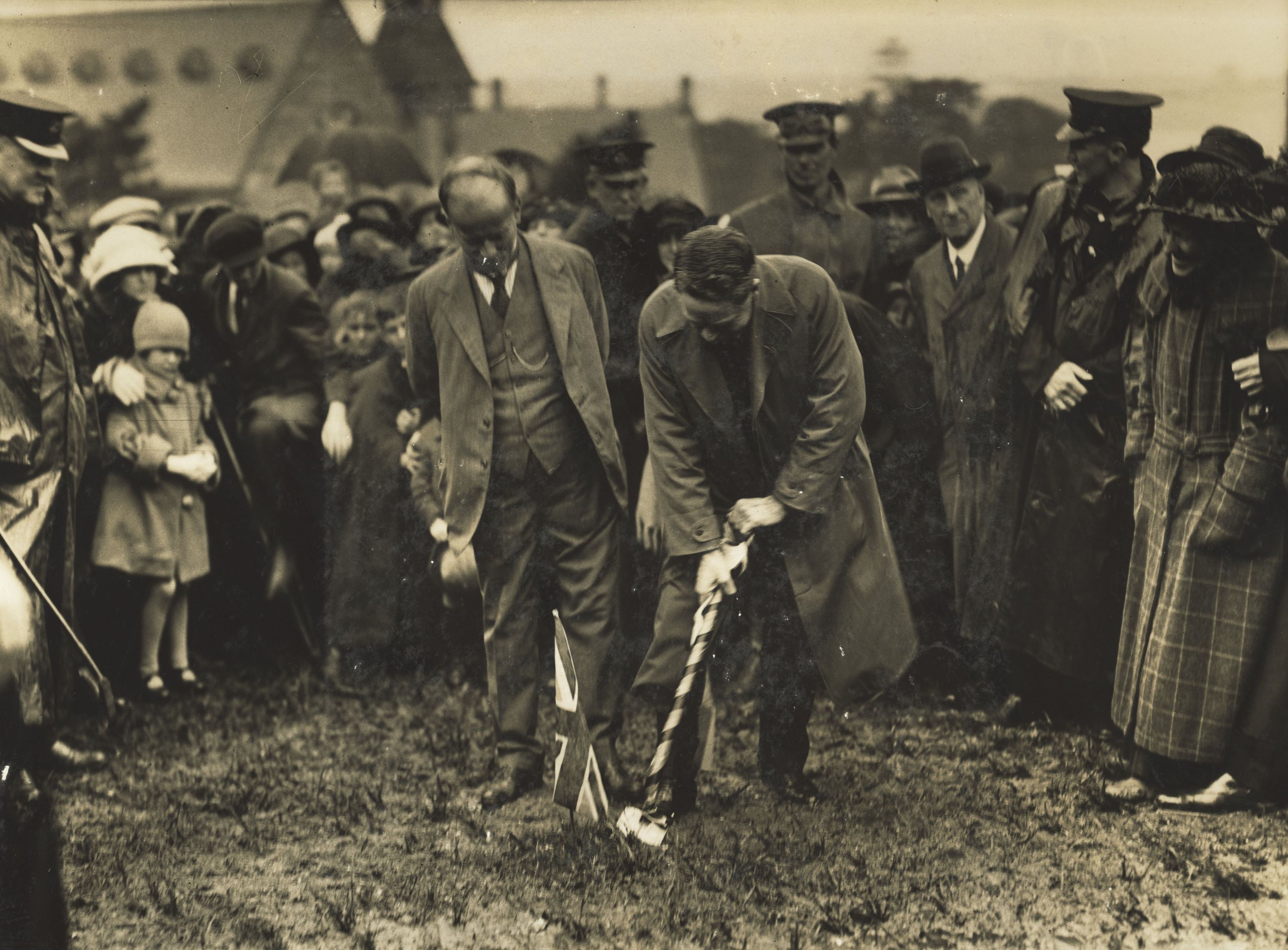 Man digging a hole in front of a crowd of onlookers