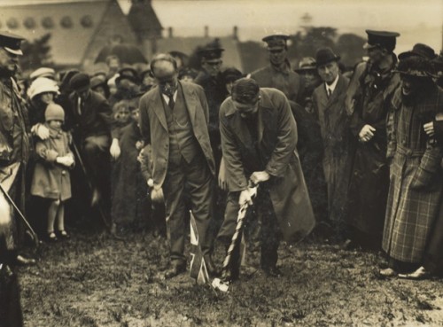 A crowd watches a man dig a hole