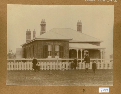 A policeman and children stand outside a police station