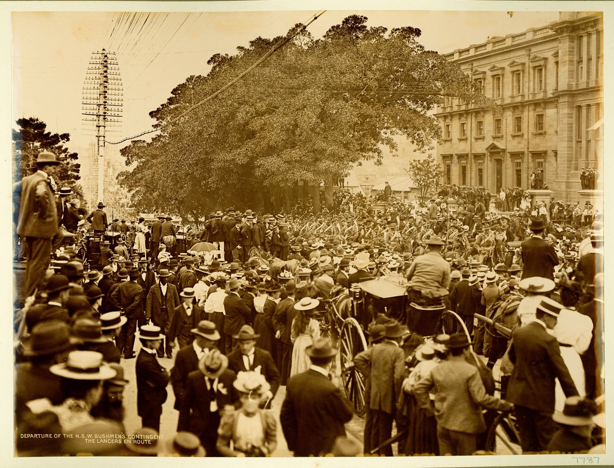 Large crowds watch troops marching down a street