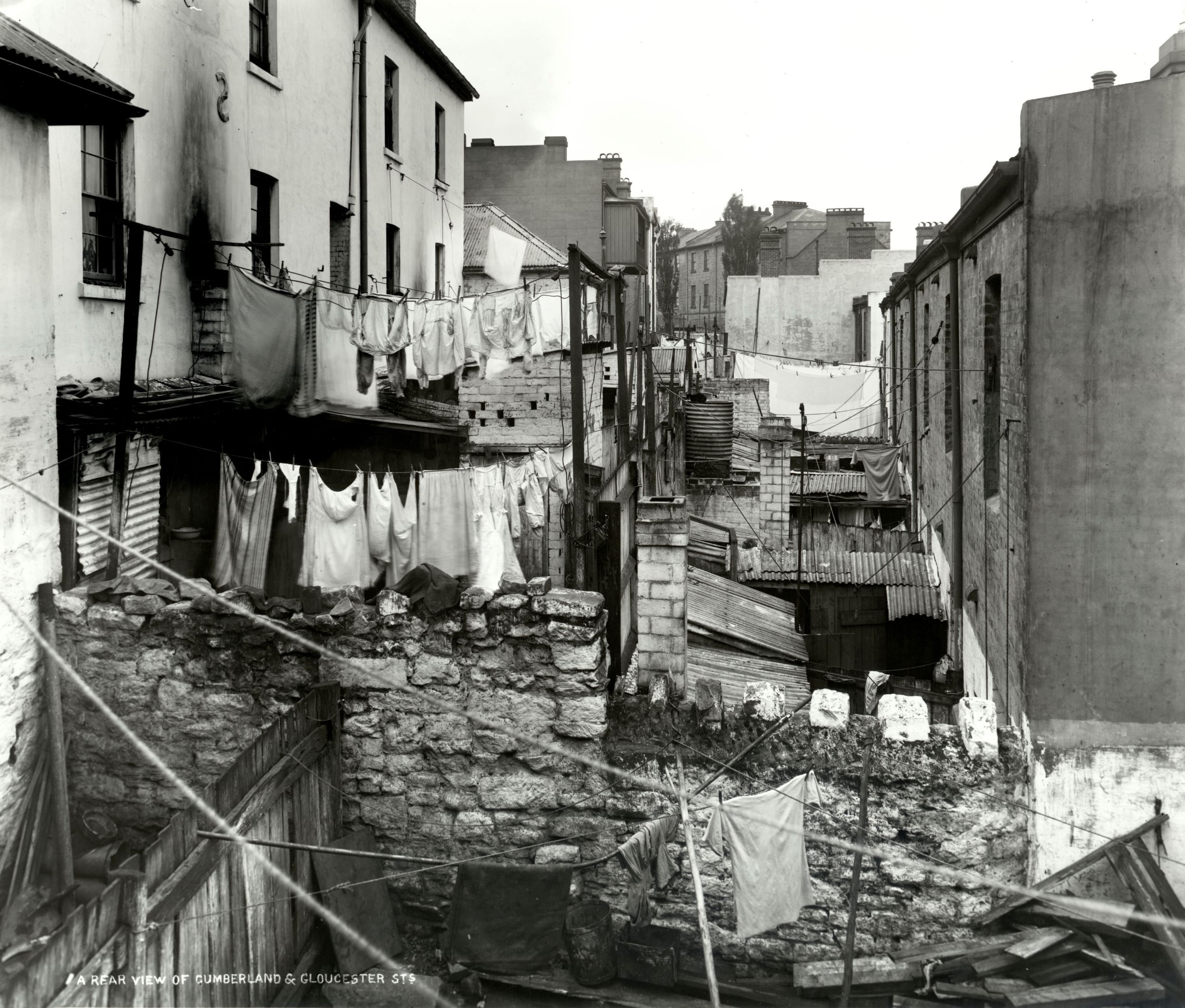 A view over a cluttered backyard lane showing crowded clothes lines strung between buildings