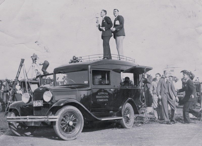 People standing on a car holding a microphone