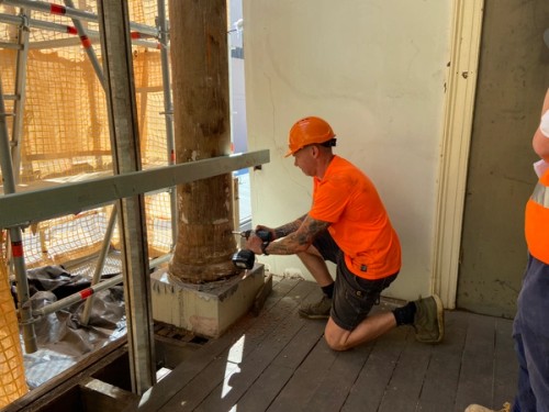 Construction worker drills into column base