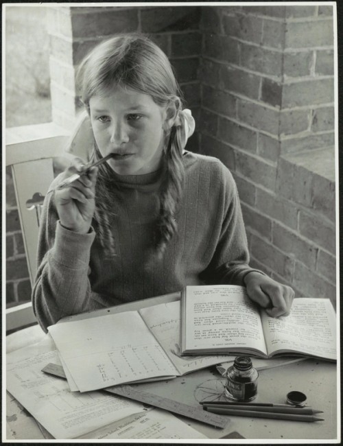 Girl studies at a table on a verandah