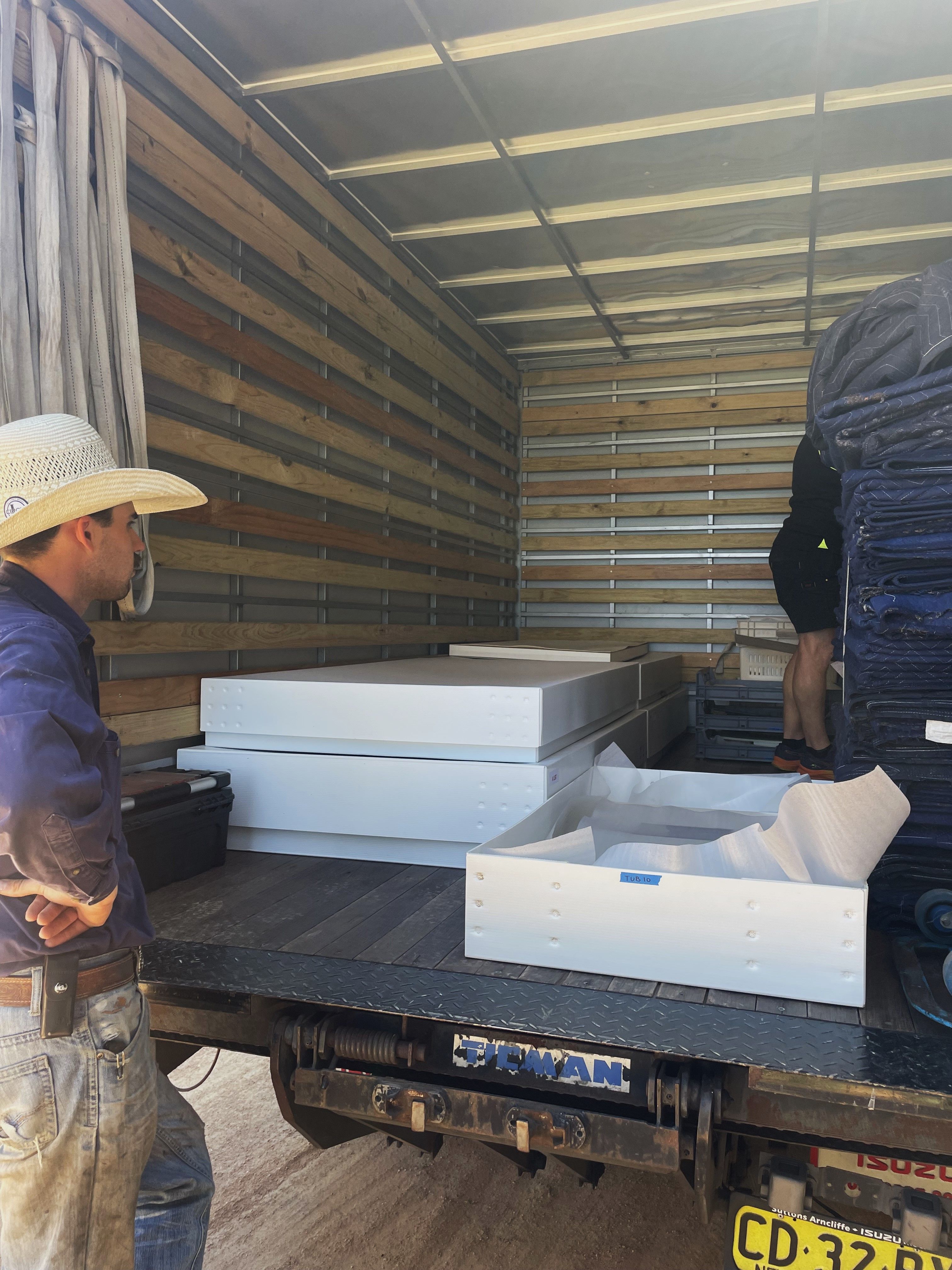 Two men packing a truck with white boxes containing collection items