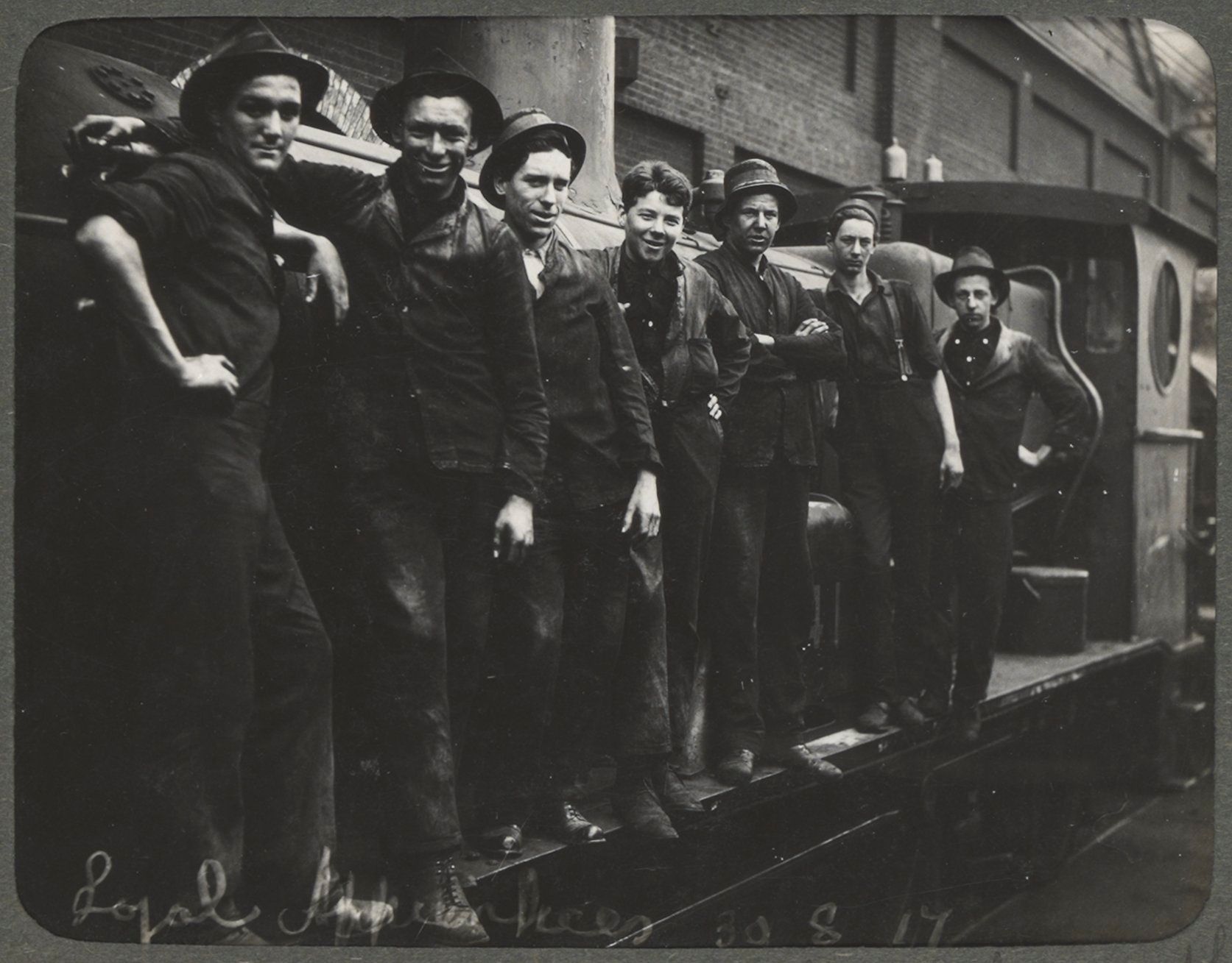 Men stand in a line on the side of a locomotive engine