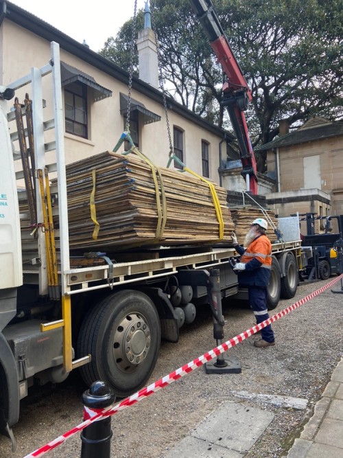 A crane lifts building supplies from a truck
