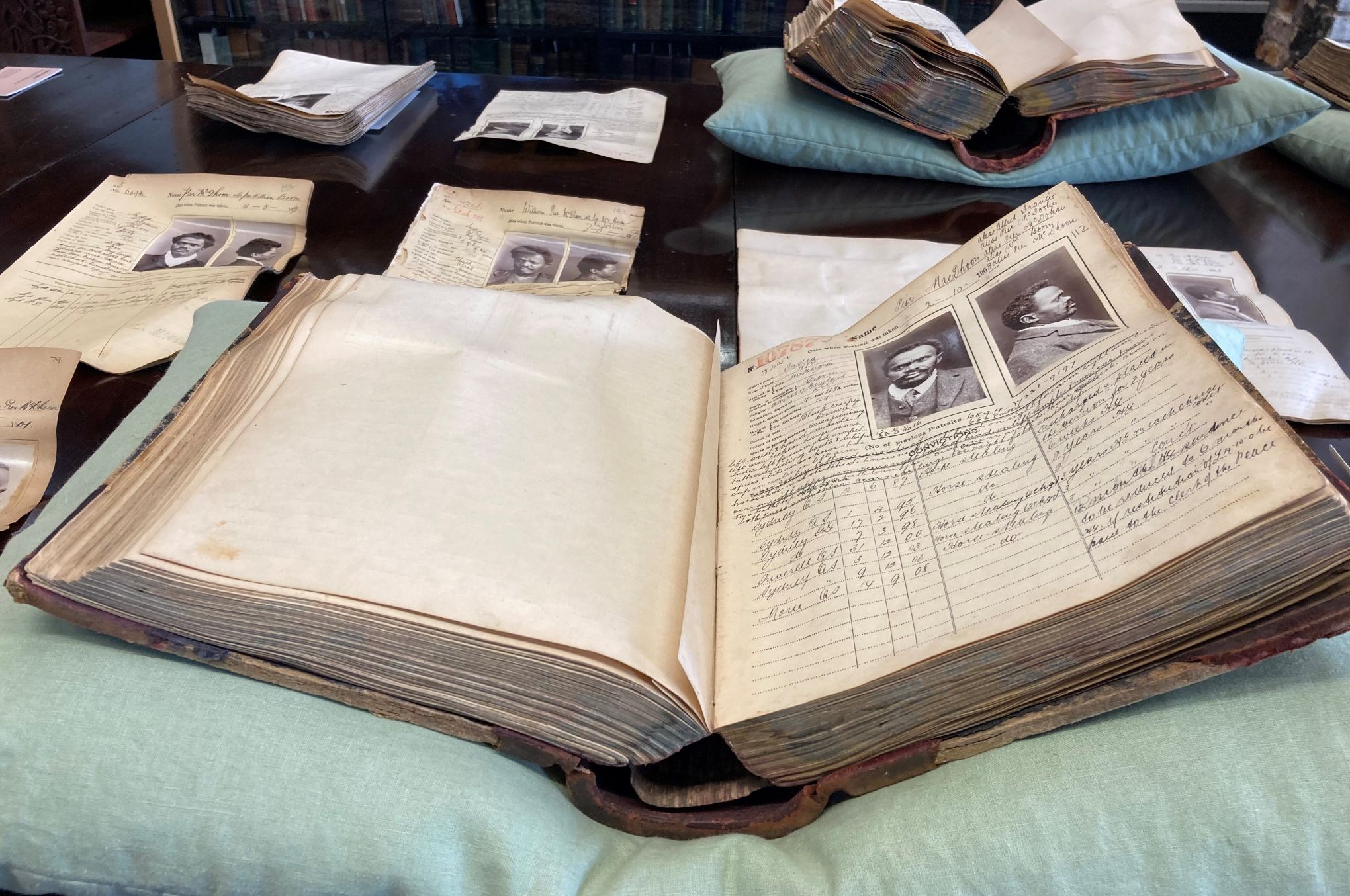 A large book open at a prisoner mugshot and description sits on a pillow