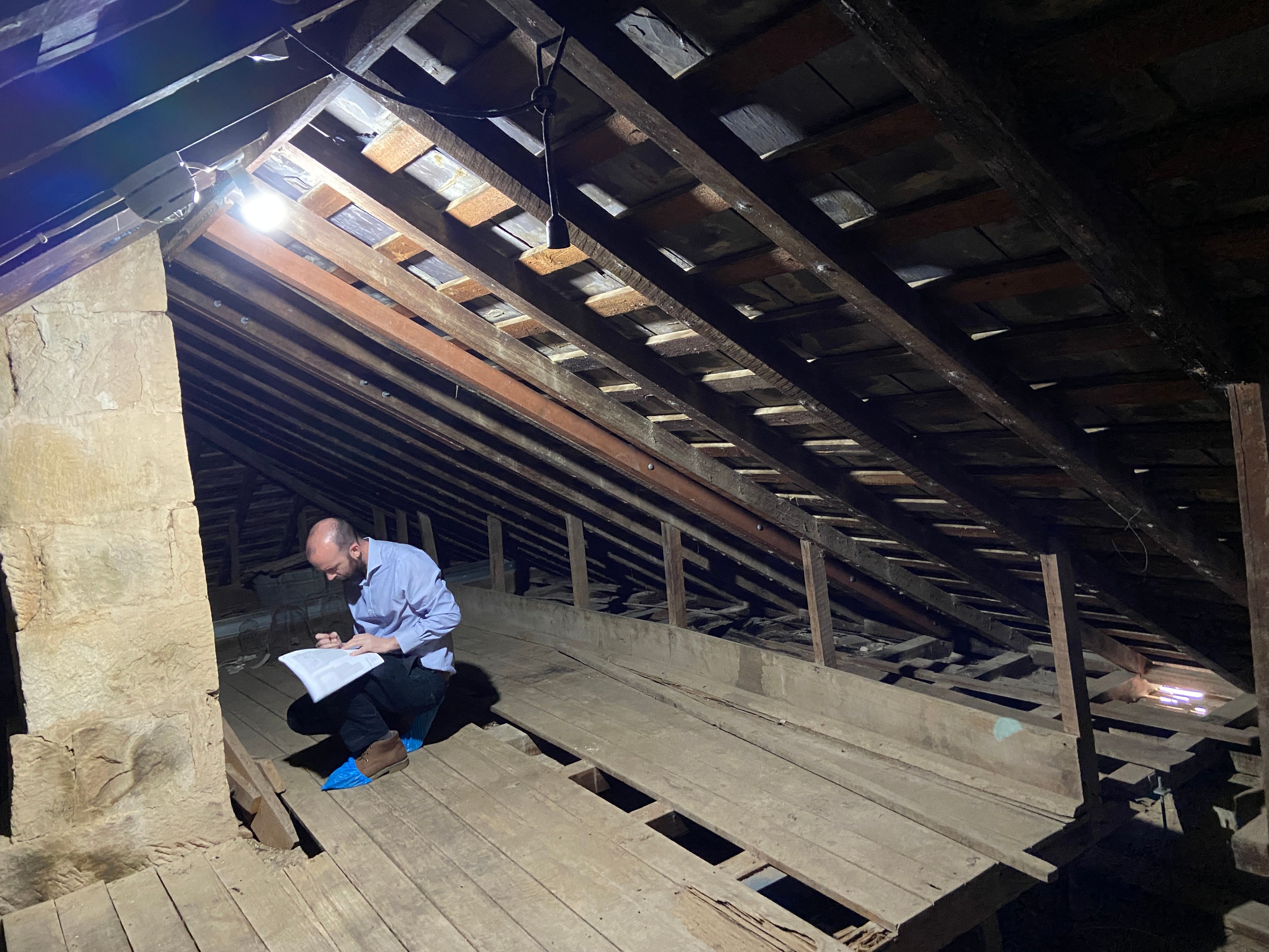 Man kneeling in a dark space and writing on a piece of paper 