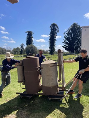 Two men pushing a heavy object on a wooden trolley 