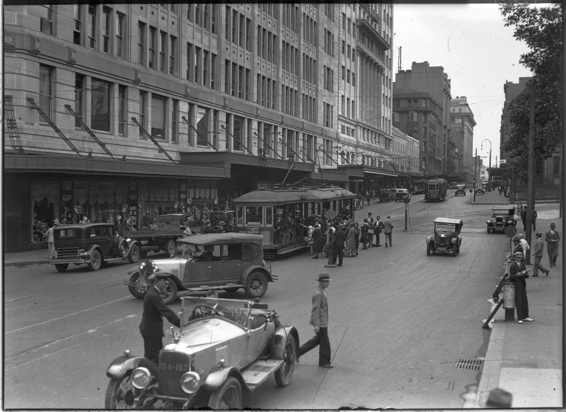 Elizabeth Street, Sydney in 1931 showing cars, shops and trams