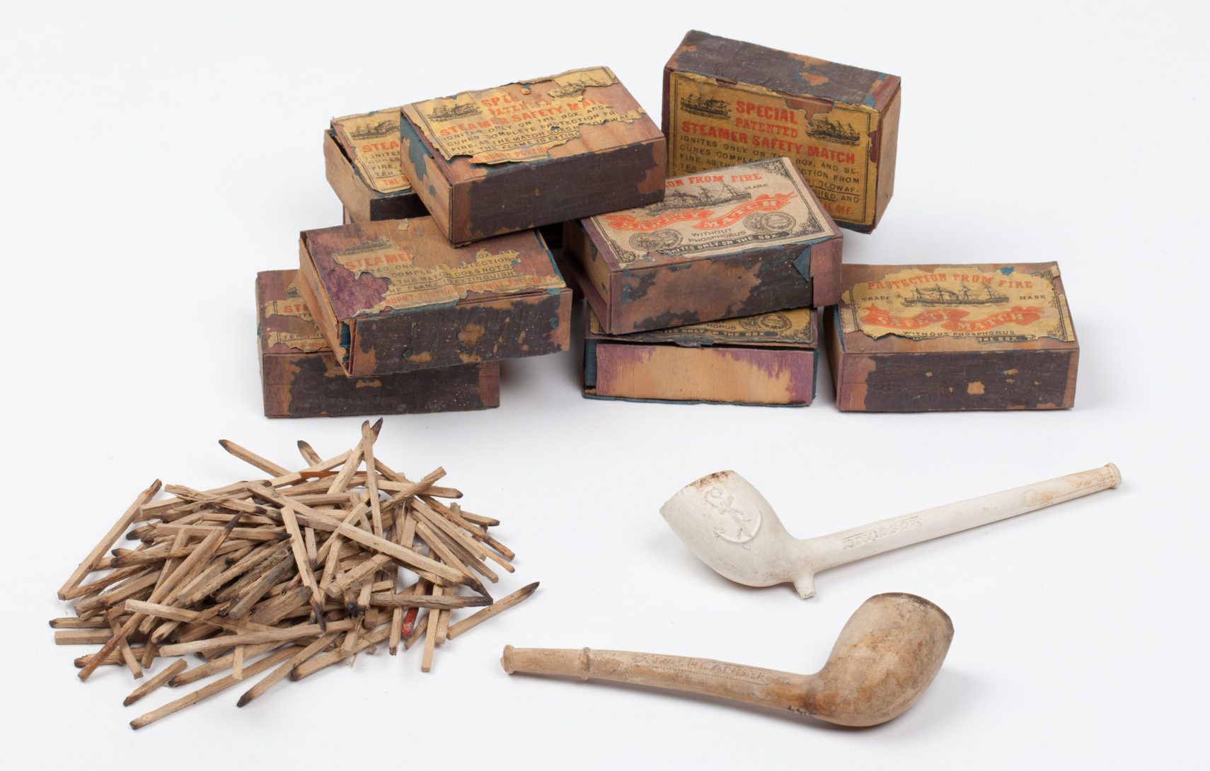 Matches, twp pipes and several boxes of mathes on a white background