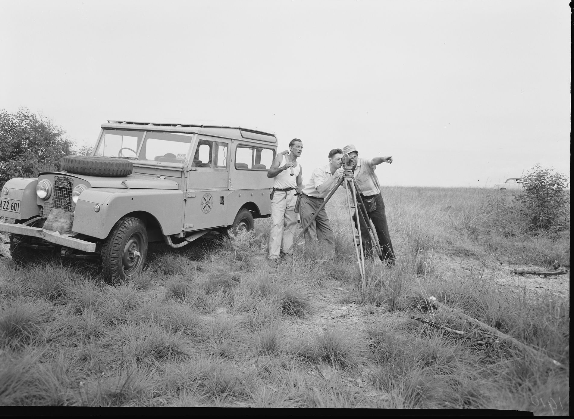 A group of surveyors with measuring instruments stranding in front of a jeep