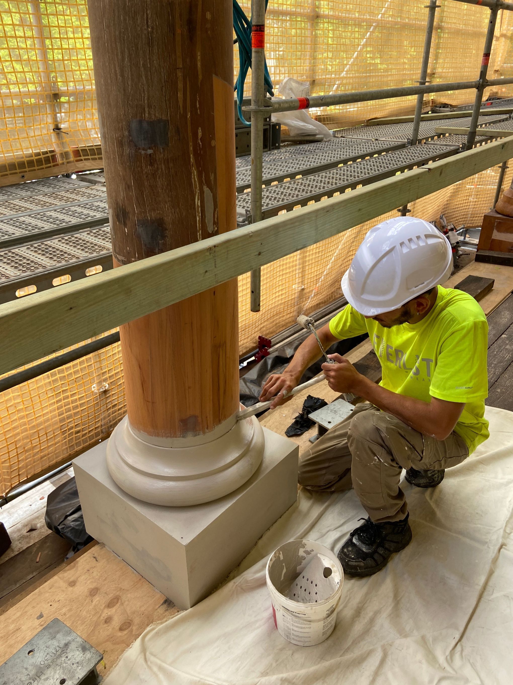 Construction worker painting the base of a wooden column
