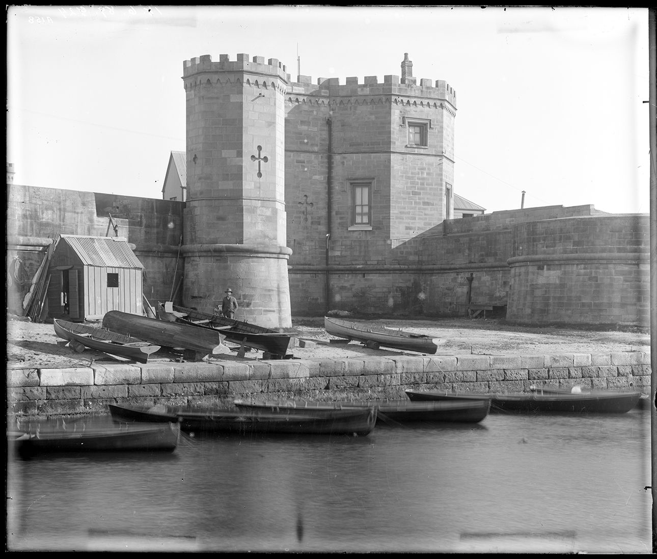 Fort Macquarie, a man stand at boats moored in front of the building