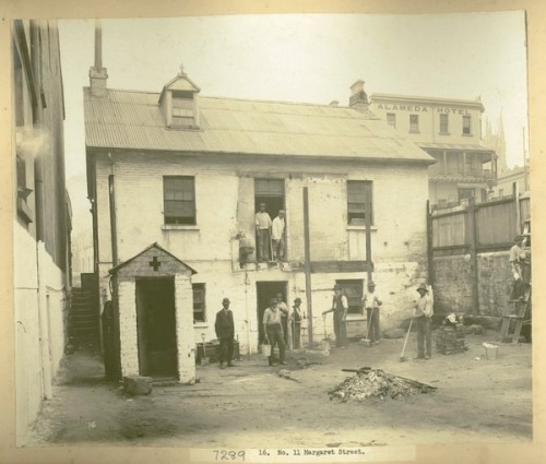 Men stand in a backyard with buckets and cleaning tools. A pile of debris is in the middle of a swept yard