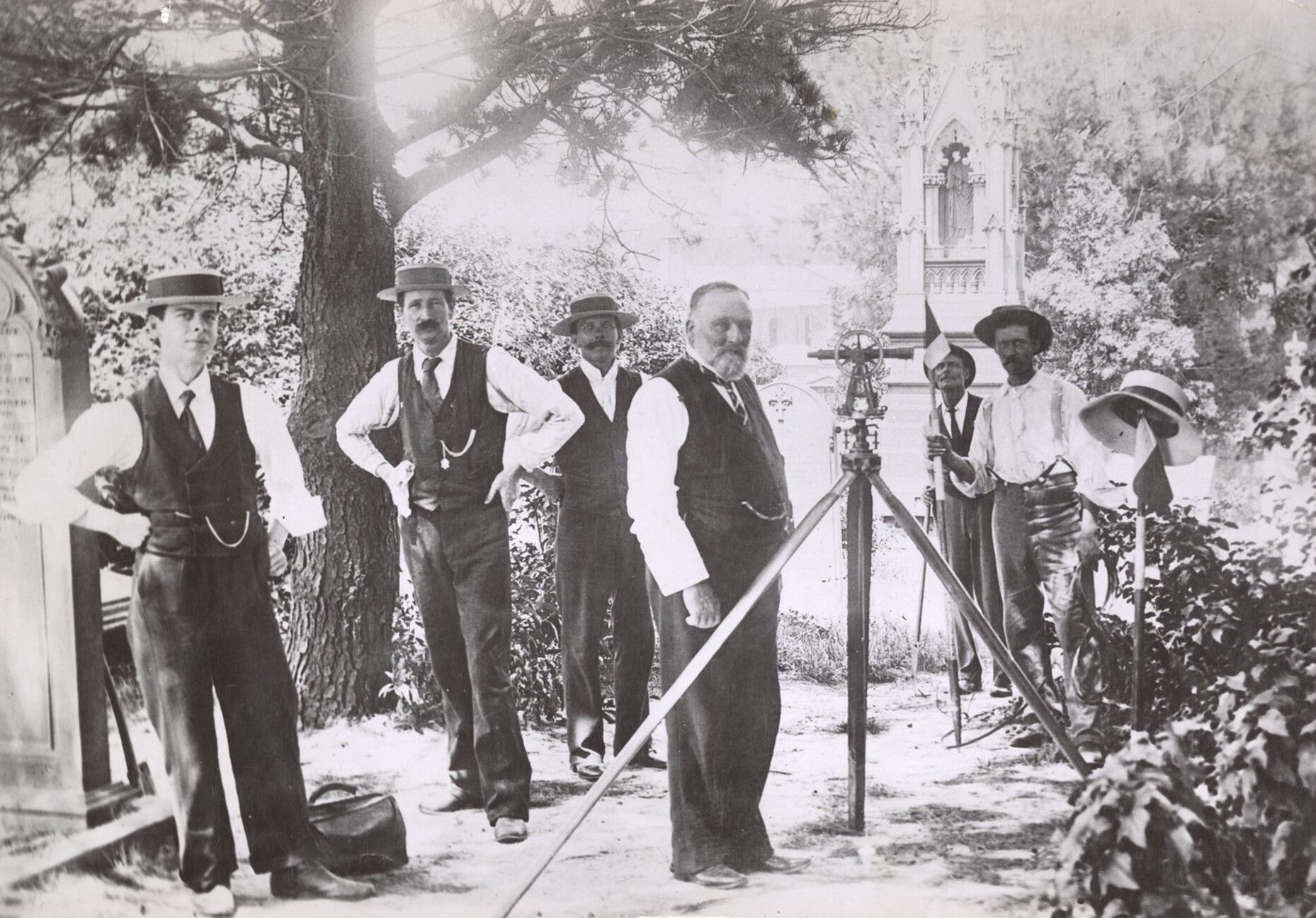 A group of men stand with their surveying equipment