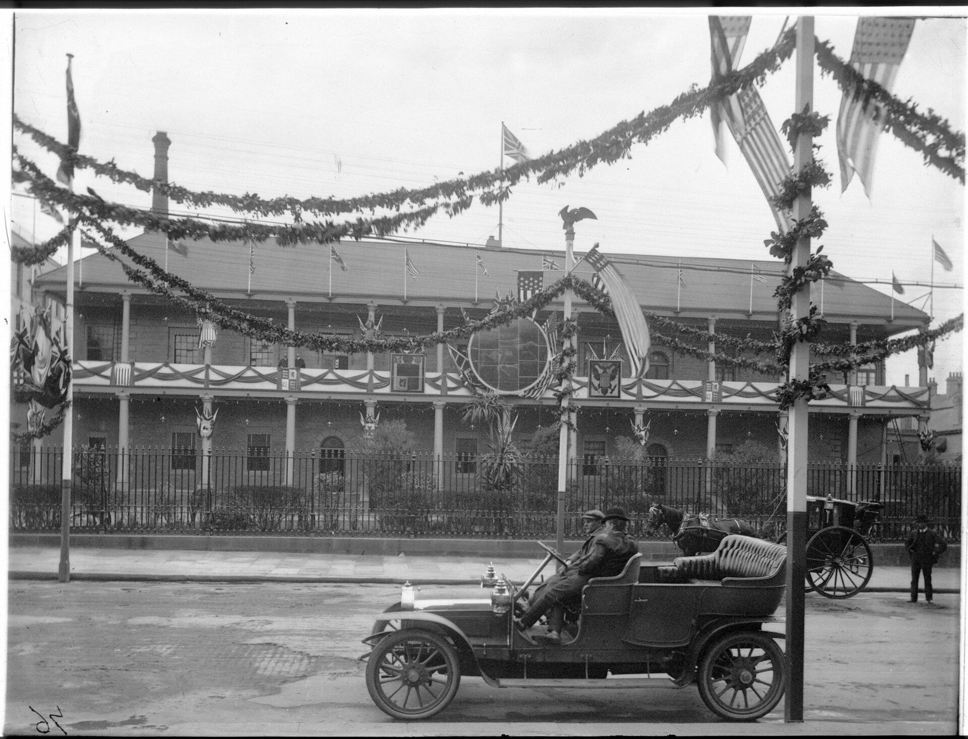 An open top car parked in front of the Mint which has been decorated with streamers and signs