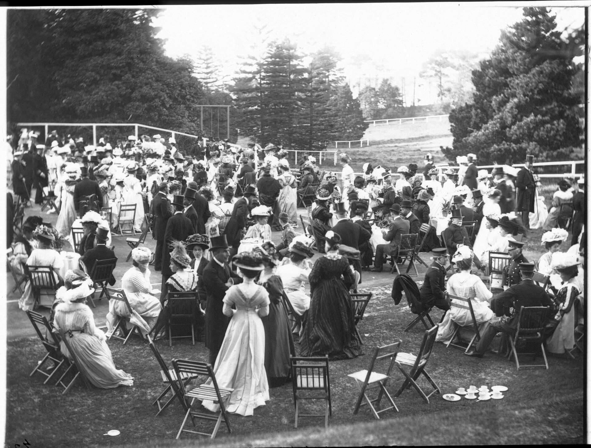  A crowded garden party of men and women in formal dress